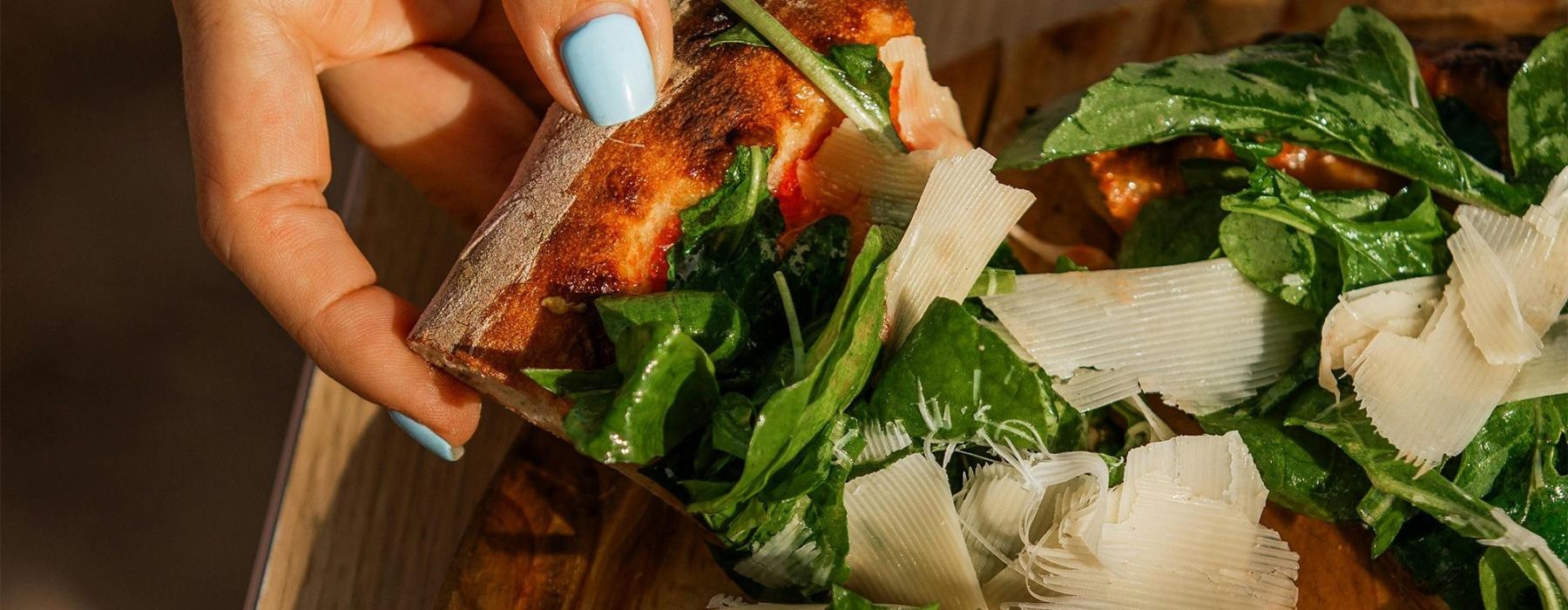 a person holding a slice of pizza